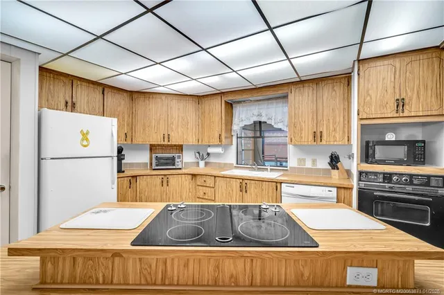 a kitchen with stainless steel appliances granite countertop a refrigerator a sink dishwasher a stove with wooden cabinets and floor