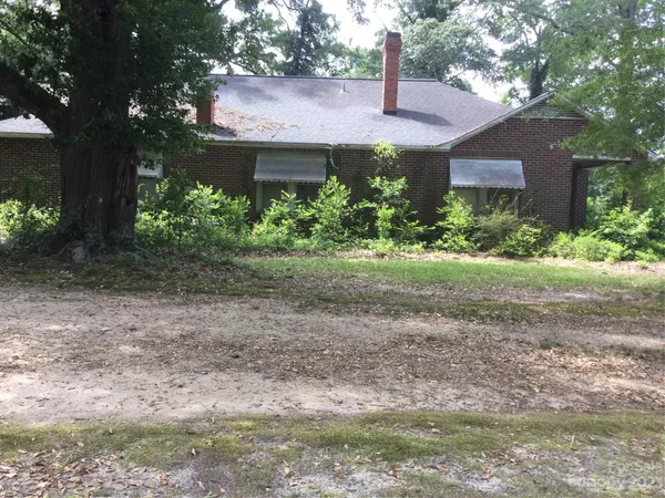 a view of a house with a yard and large tree