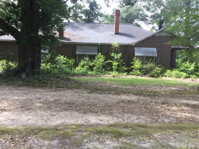 a view of a house with a yard and large tree