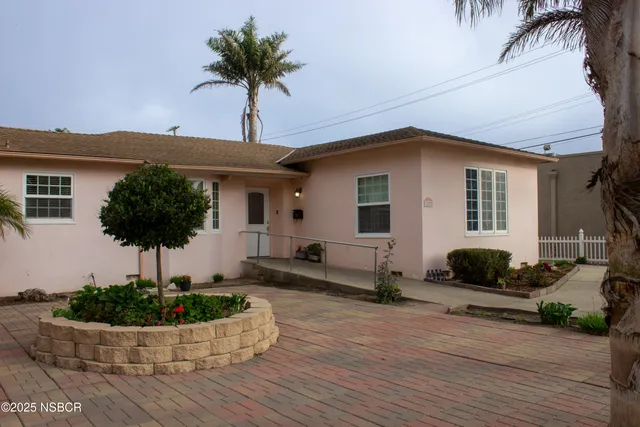 a front view of a house with a yard and potted plants