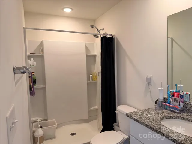 a bathroom with a granite countertop sink toilet and shower