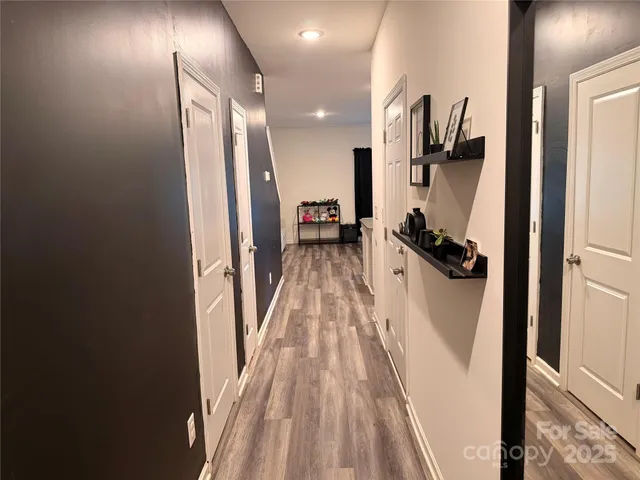 a view of a hallway with wooden floor and a bathroom