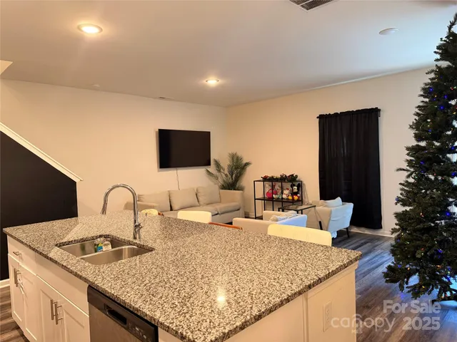 a kitchen with granite countertop a sink and a stove top oven with wooden floor