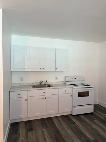 a kitchen with granite countertop white cabinets and white appliances