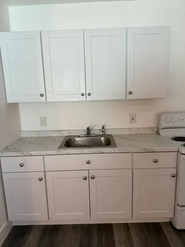 a kitchen with white cabinets and sink