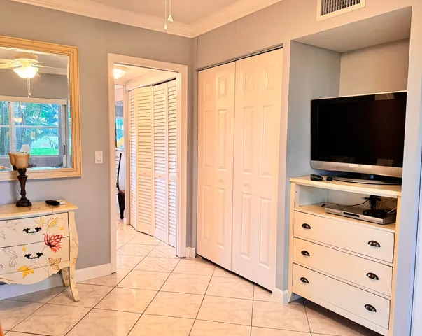 a room with a flat screen tv on the dresser and a window