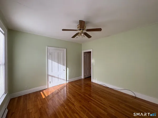 a view of empty room with wooden floor and fan