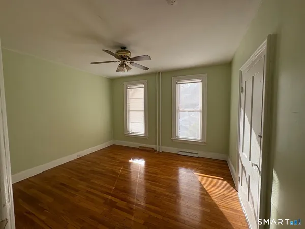 a view of empty room with wooden floor and fan