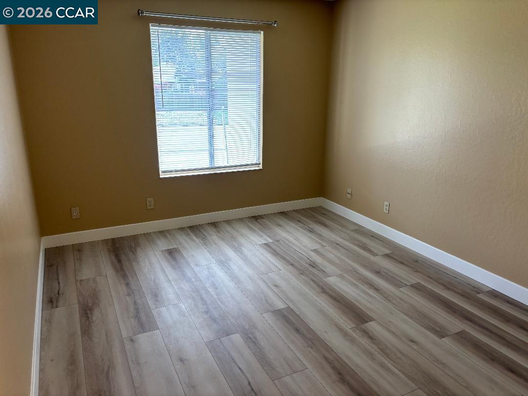 5460 Concord Boulevard, Unit B7 Concord, CA 94521 - Photo 11 of 20 a view of an empty room with wooden floor and a window