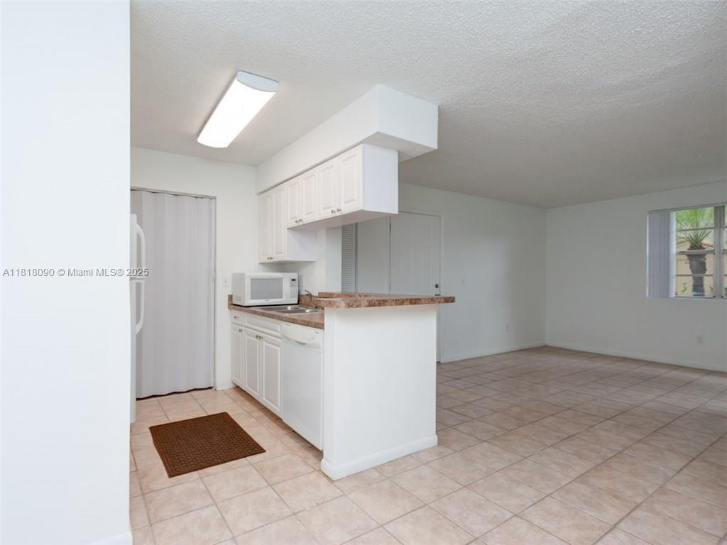 1235 Southwest 46th Avenue, Unit 707 Pompano Beach, FL 33069 - Photo 5 of 15 a kitchen with a cabinets and white appliances