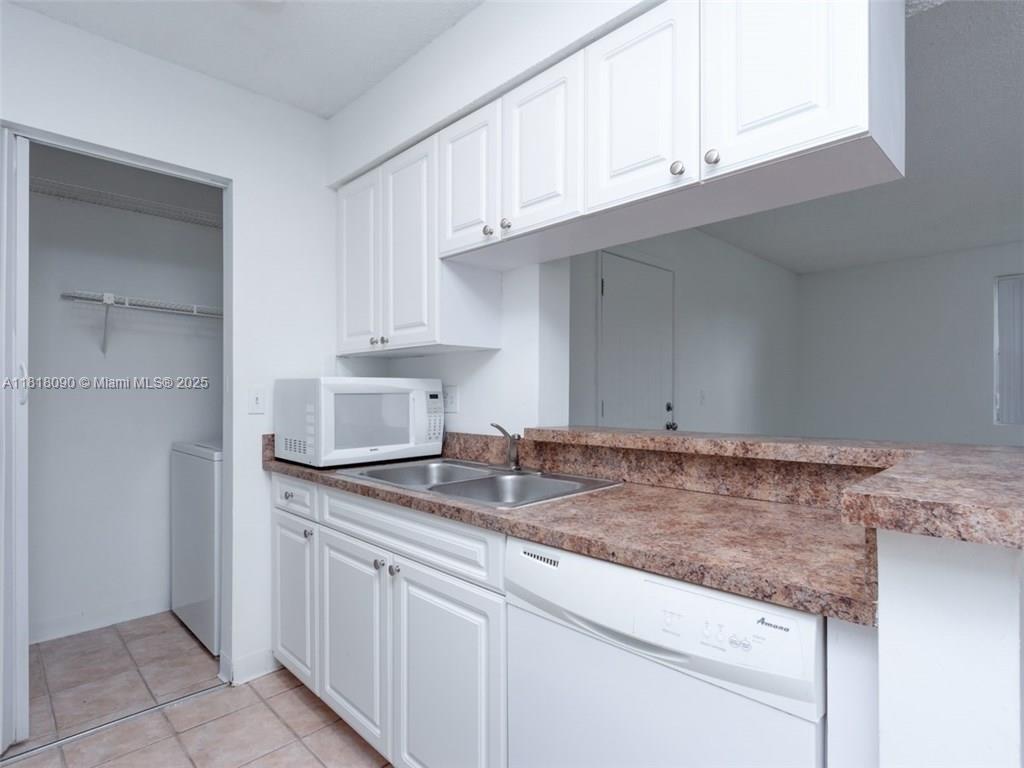 1235 Southwest 46th Avenue, Unit 707 Pompano Beach, FL 33069 - Photo 6 of 15 a kitchen with granite countertop a sink and cabinets