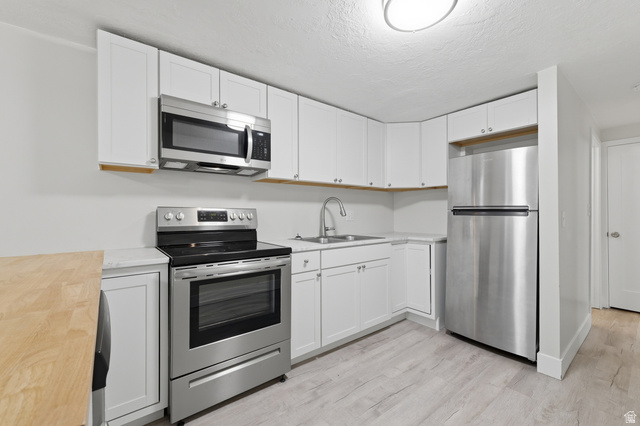 831 Lennox Street, Unit 5 Midvale, UT 84047 - Photo 11 of 19 Kitchen featuring stainless steel appliances, white cabinets, light wood-type flooring, butcher block countertops, and a textured ceiling