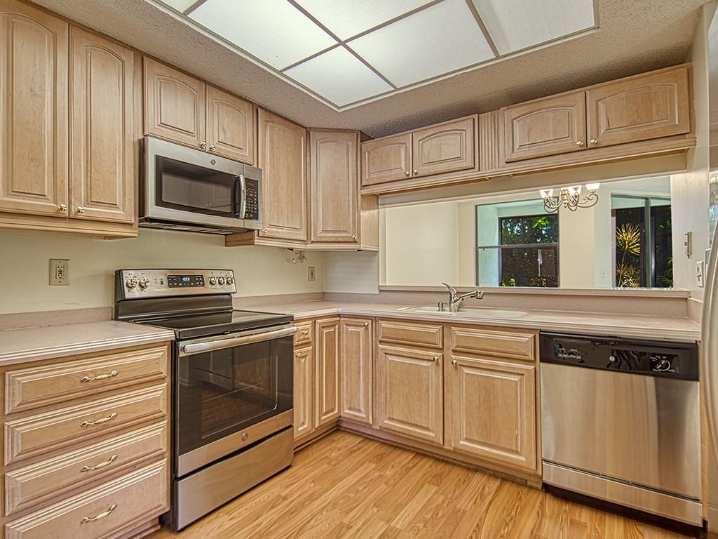 5270 Southeast Seascape Way, Unit 103 Stuart, FL 34997 - Photo 4 of 21 a kitchen with stainless steel appliances granite countertop a sink a stove a microwave and cabinets
