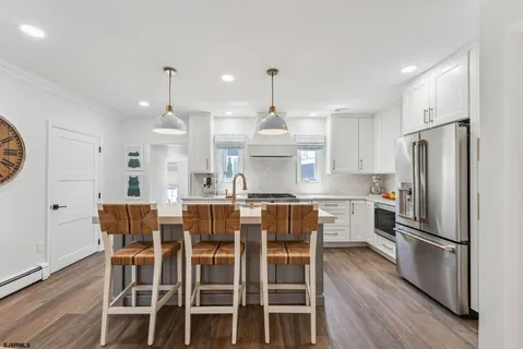 a kitchen with stainless steel appliances kitchen island granite countertop a dining table chairs and white cabinets