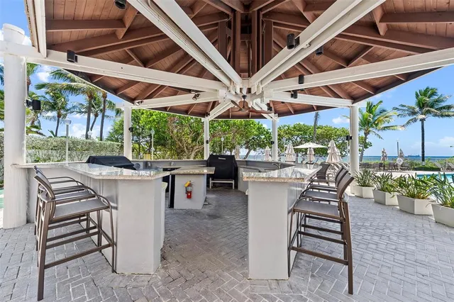 a view of a patio with a table and chairs under an umbrella with a barbeque