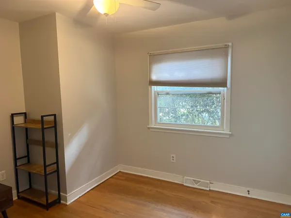 an empty room with wooden floor closet and windows