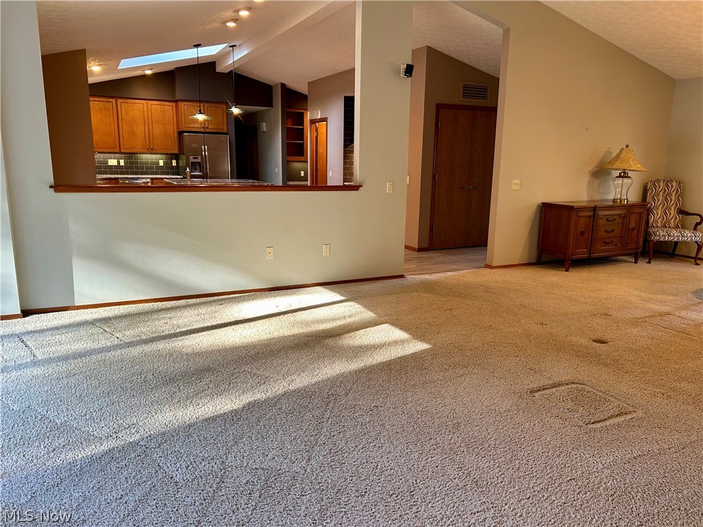 8763 Timber Edge Drive North Ridgeville, OH 44039 - Photo 14 of 40 Unfurnished living room featuring vaulted ceiling with skylight and light colored carpet