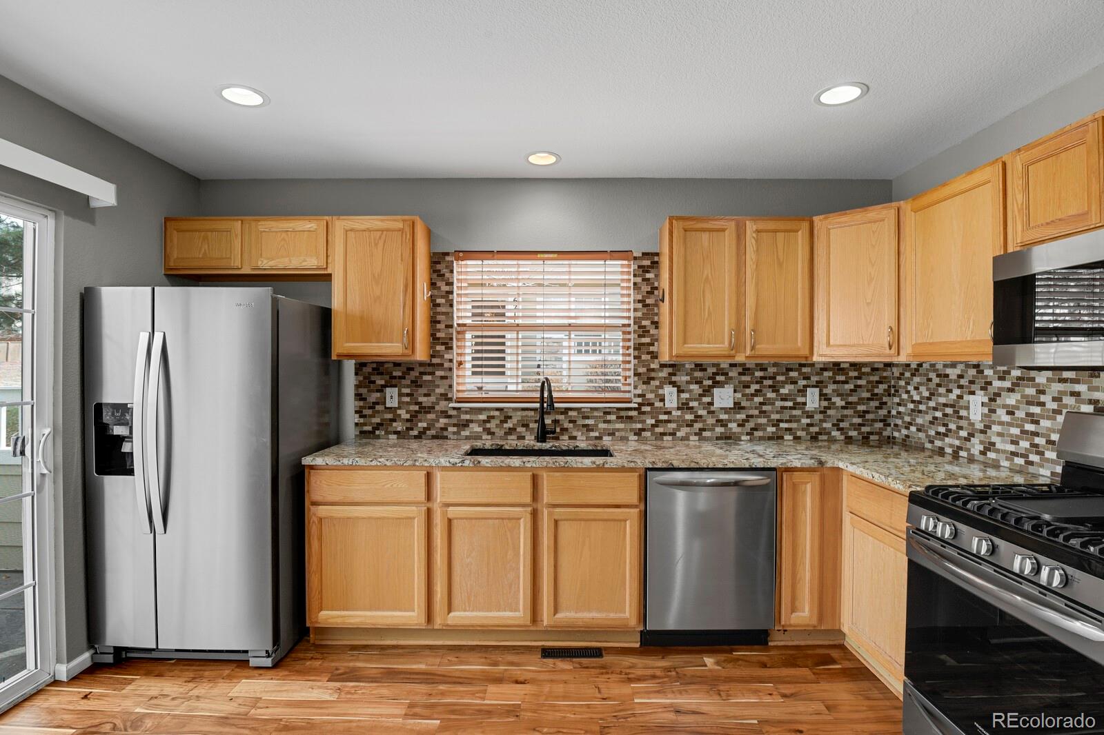 6141 Trailhead Road Highlands Ranch, CO 80130 - Photo 13 of 42 a kitchen with stainless steel appliances granite countertop a sink stove and refrigerator