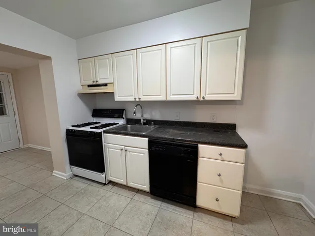 a kitchen with granite countertop white cabinets and appliances