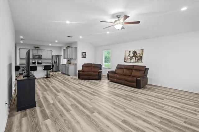 a living room with furniture kitchen view and a wooden floor