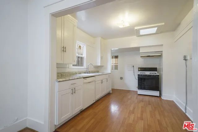 a large kitchen with a wooden floor and stainless steel appliances