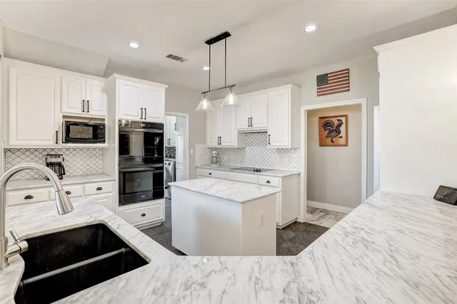 a large white kitchen with stainless steel appliances kitchen island granite countertop a stove and refrigerator