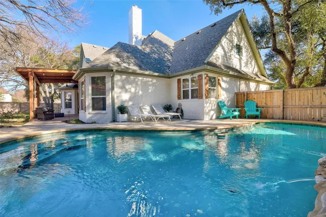 a view of swimming pool with lawn chairs and plants