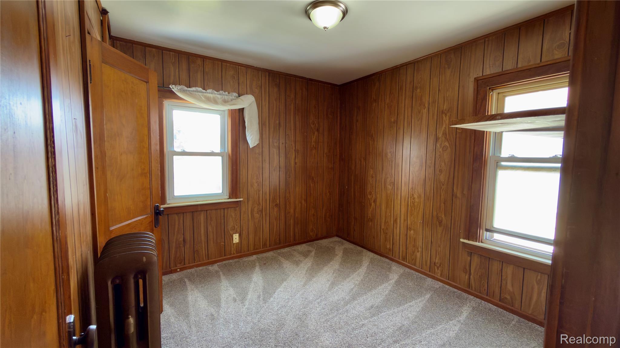130 Elm Street River Rouge, MI 48218 - Photo 16 of 20 Room featuring wood paneling on walls, two single-hung windows, and light gray patterned carpeting