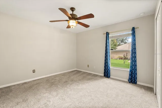 an empty room with ceiling fan and window