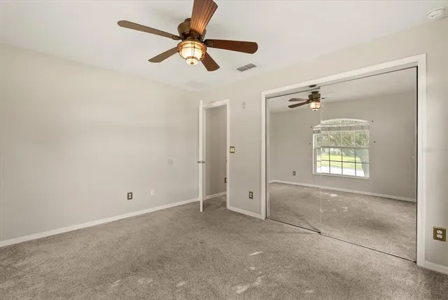 an empty room with fan and windows