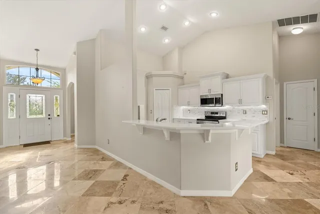 a kitchen with stainless steel appliances granite countertop a refrigerator a sink dishwasher and white cabinets with wooden floor