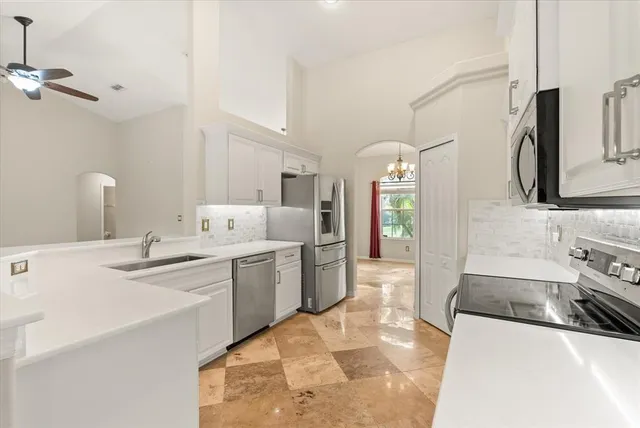 a large white kitchen with stainless steel appliances granite countertop a sink dishwasher a stove and a refrigerator with wooden floor