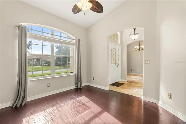 a view of an empty room with wooden floor and a window