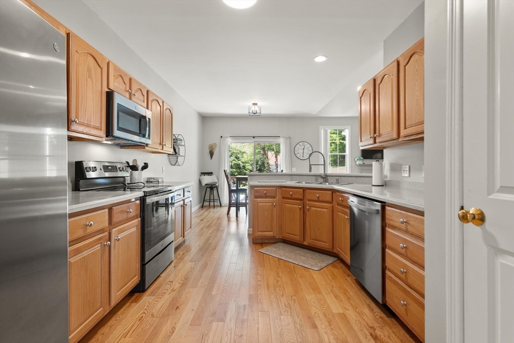27 Brook Lane, Unit 27 Berlin, MA 01503 - Photo 9 of 36 a large kitchen with stainless steel appliances granite countertop a stove a sink dishwasher and a microwave oven with wooden floor
