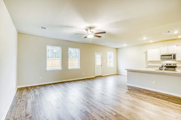 a view of an empty room with window and wooden floor