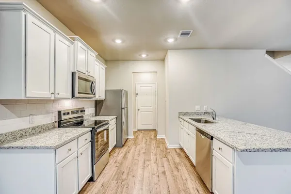a kitchen with stainless steel appliances granite countertop a stove a sink and a refrigerator