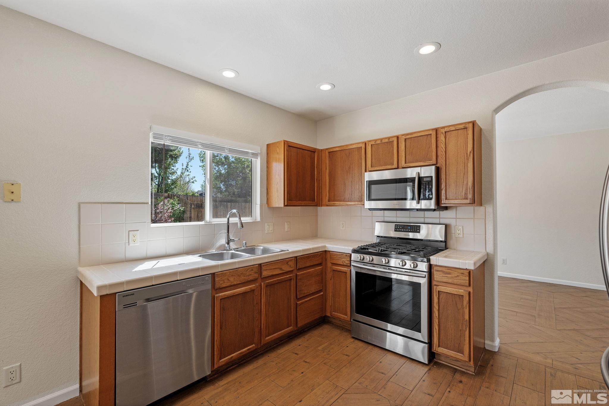 10015 Stonefield Drive Reno, NV 89521 - Photo 11 of 35 a kitchen with stainless steel appliances granite countertop a sink stove and microwave