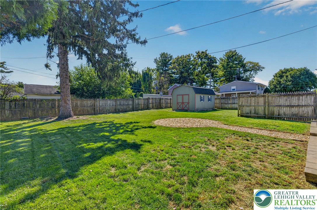 1814 Ruth Street Allentown, PA 18104 - Photo 51 of 54 Mature trees and a wooden privacy fence frame a spacious lawn featuring a storage shed.