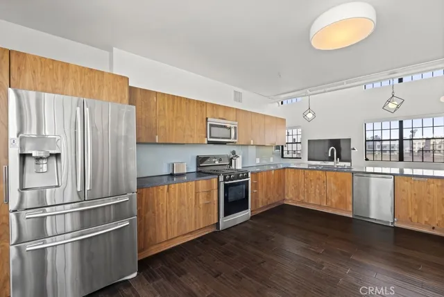 a kitchen with stainless steel appliances granite countertop a refrigerator a sink dishwasher a stove and white countertops with wooden floor