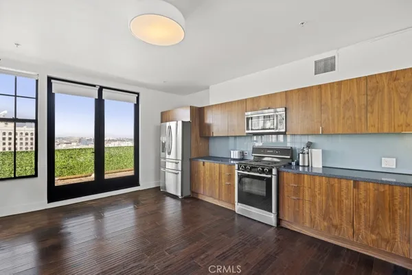 a kitchen with stainless steel appliances granite countertop a refrigerator a sink dishwasher a stove and white countertops with wooden floor