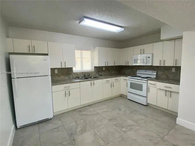 a white cabinets with sink and microwave
