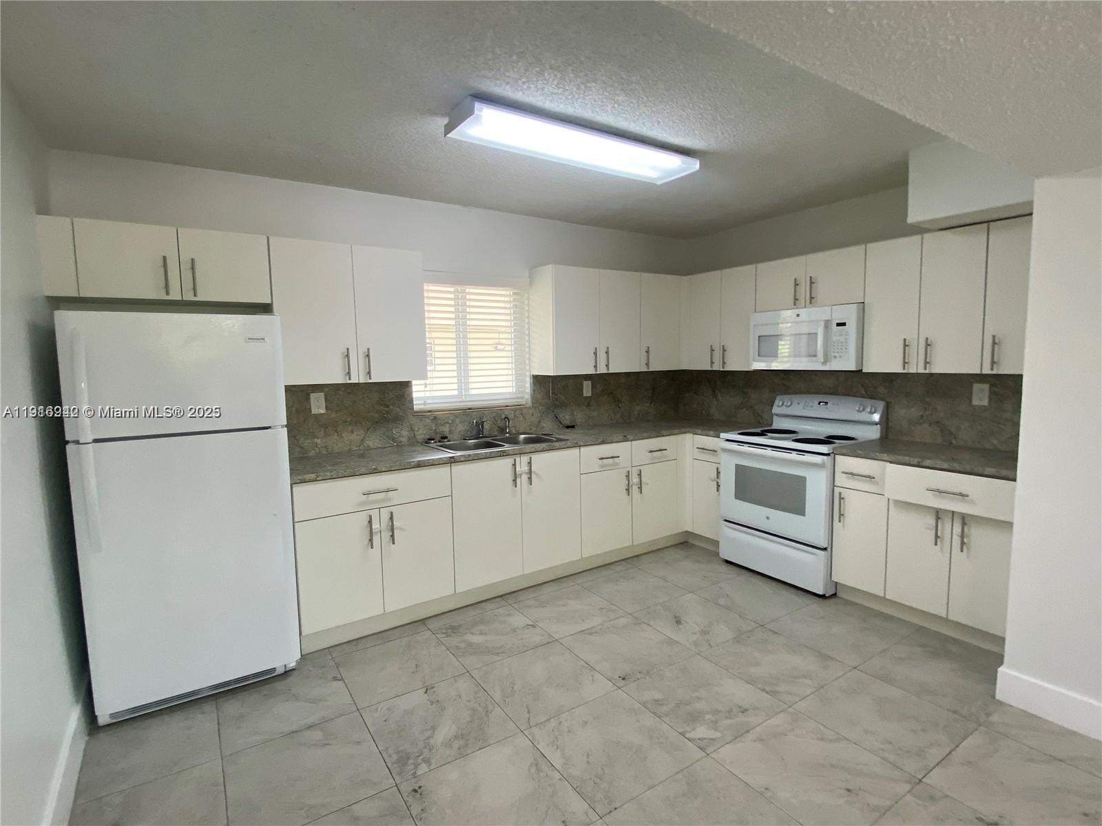 1650 West 44th Place, Unit 227 Hialeah, FL 33012 - Photo 2 of 9 a white cabinets with sink and microwave