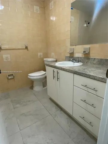 a bathroom with a granite countertop toilet sink and mirror