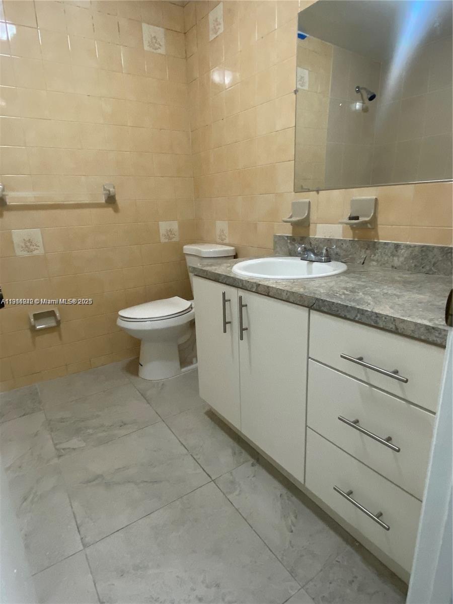 1650 West 44th Place, Unit 227 Hialeah, FL 33012 - Photo 6 of 9 a bathroom with a granite countertop toilet sink and mirror