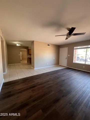 a view of empty room with wooden floor and fan