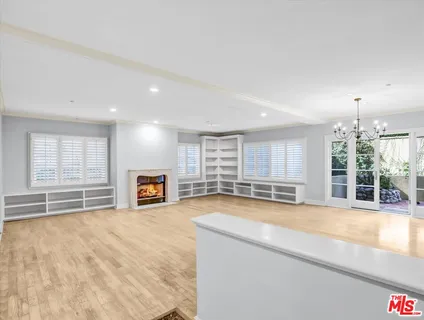 a view of an empty room with wooden floor and a kitchen