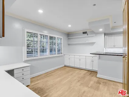 a large kitchen with granite countertop a sink and white cabinets