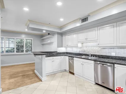 a kitchen with granite countertop white cabinets and appliances