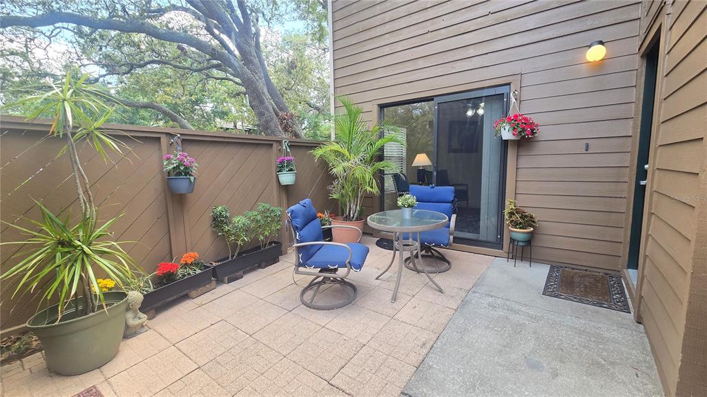 103 Cypress Pond Road, Unit 103 Palm Harbor, FL 34683 - Photo 4 of 52 a view of a patio with table and chairs potted plants and a large tree