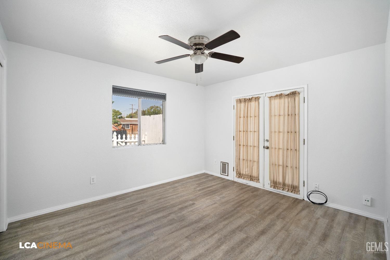 Undisclosed Address Bakersfield, CA 93305 - Photo 13 of 20 an empty room with wooden floor ceiling fan and windows